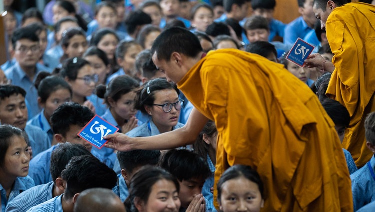 Asistentes moviéndose entre la audiencia con objetos rituales mientras Su Santidad el Dalái Lama otorga la iniciación de permiso de Manjushri Blanco en el último día de sus enseñanzas para jóvenes estudiantes tibetanos en el Templo Principal Tibetano en Dharamsala, HP, India el 8 de junio de 2018. Foto de Tenzin Choejor