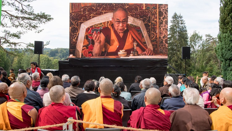 Miembros de la multitud observando a Su Santidad el Dálai Lama en una pantalla grande fuera del templo durante la ceremonia de conmemoración del 50º aniversario del Tibet Institute Rikon en Rikon, Suiza, el 21 de septiembre de 2018. Foto de Manuel Bauer