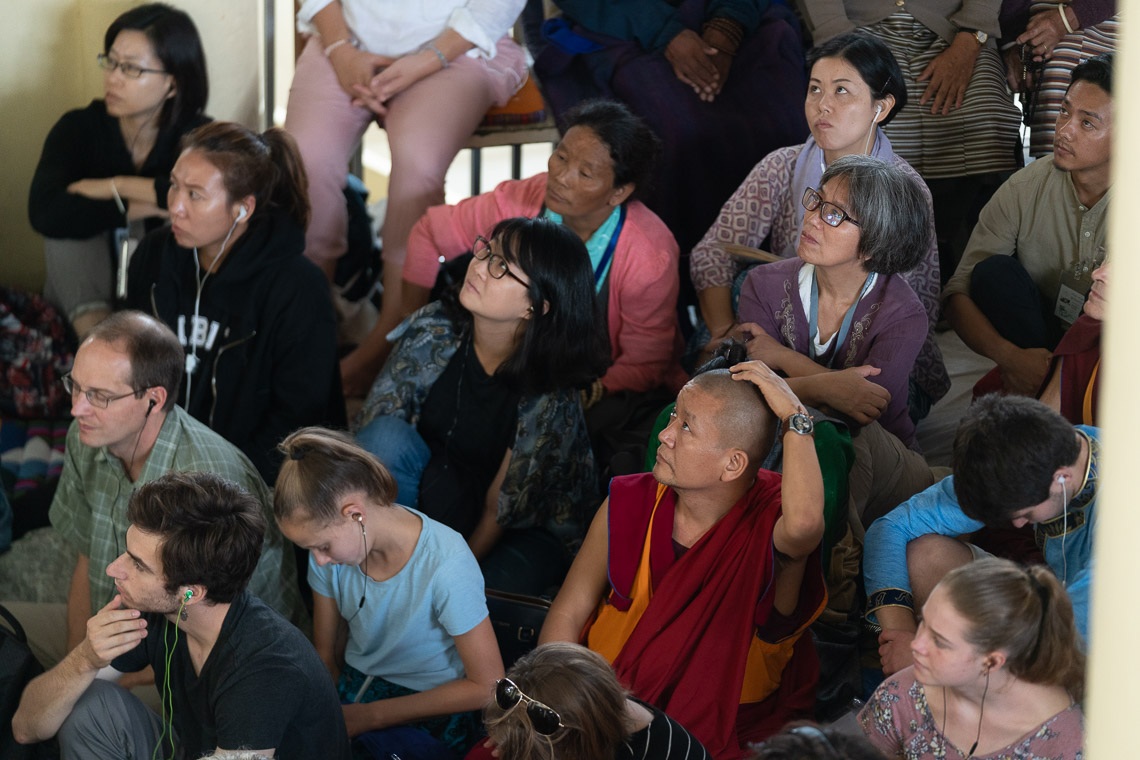 Miembros de la audiencia sentados en la terraza fuera del Templo Principal Tibetano viendo a Su Santidad el Dalái Lama en una pantalla de televisión durante el primer día de sus enseñanzas en Dharamsala, HP, India, el 4 de septiembre de 2019. Foto de Tenzin Choejor