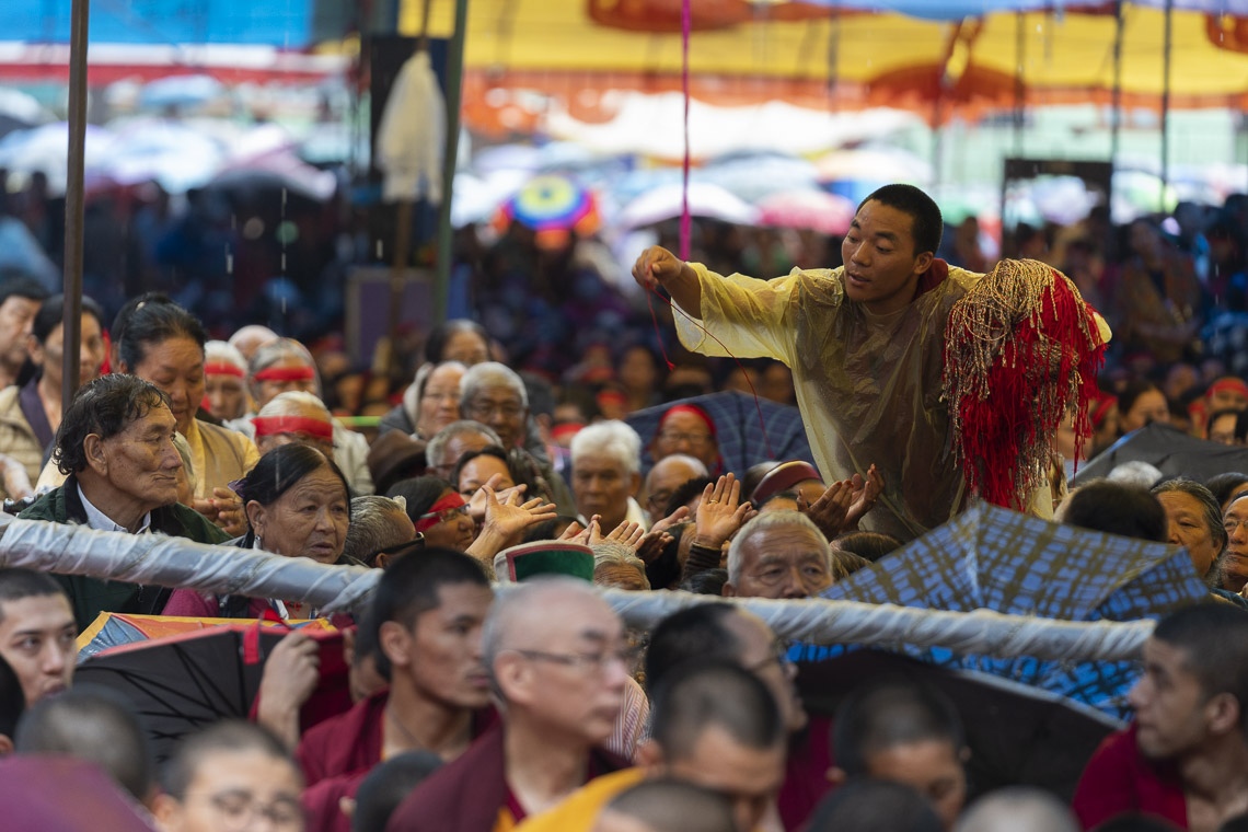 Un voluntario repartiendo cordeles de protección ritual mientras Su Santidad el Dalái Lama otorga el Empoderamiento de Mahakarunika Lokeshvara en Manali, HP, India, el 17 de agosto de 2019. Foto de Tenzin Choejor